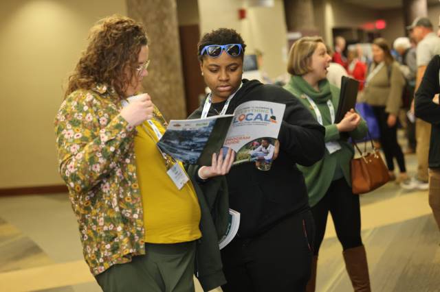 Two women looking at a conference pamphlet at the Everything Local Conference.