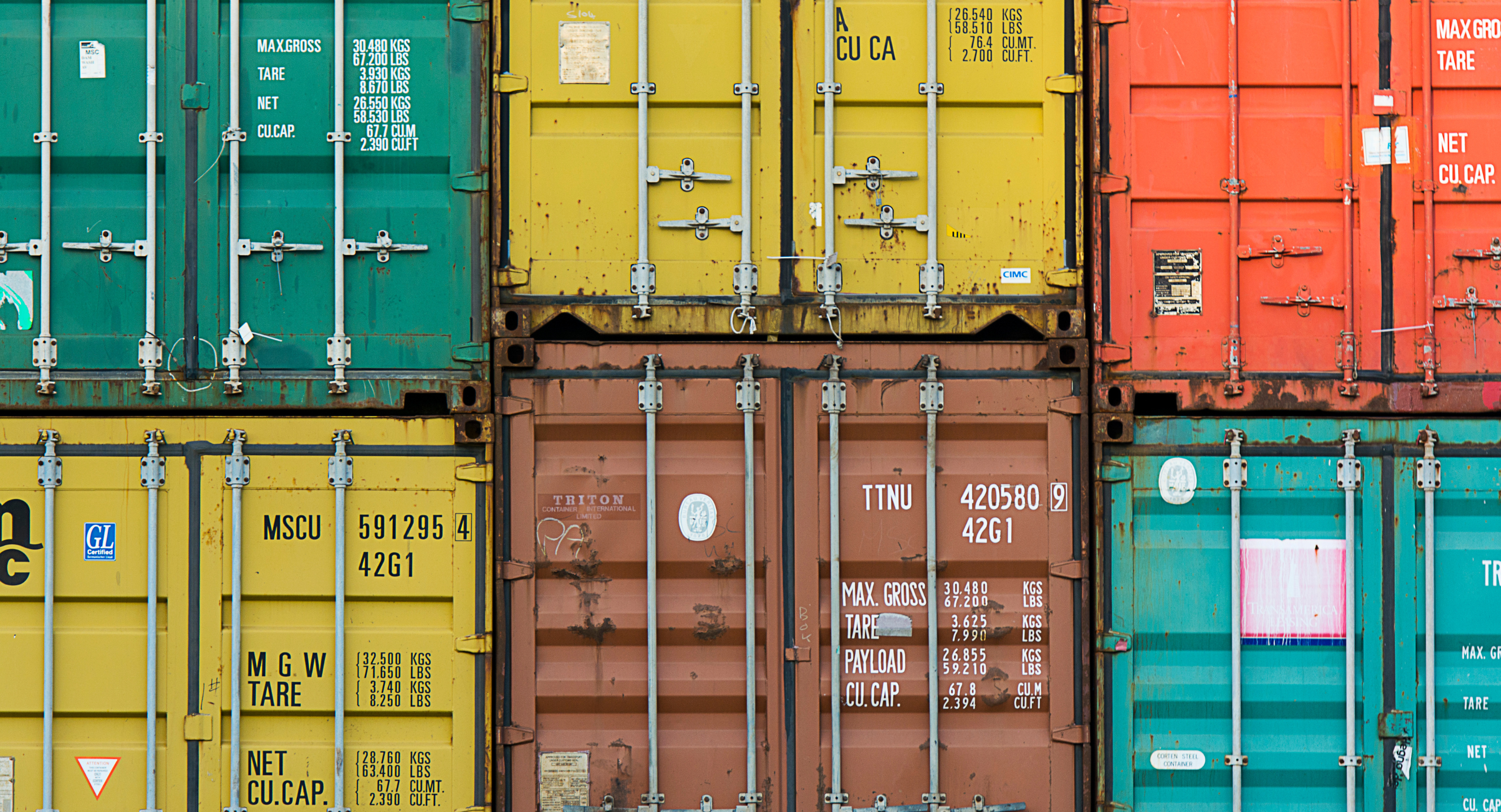 Six vibrant cargo shipping containers stacked on top of one another.