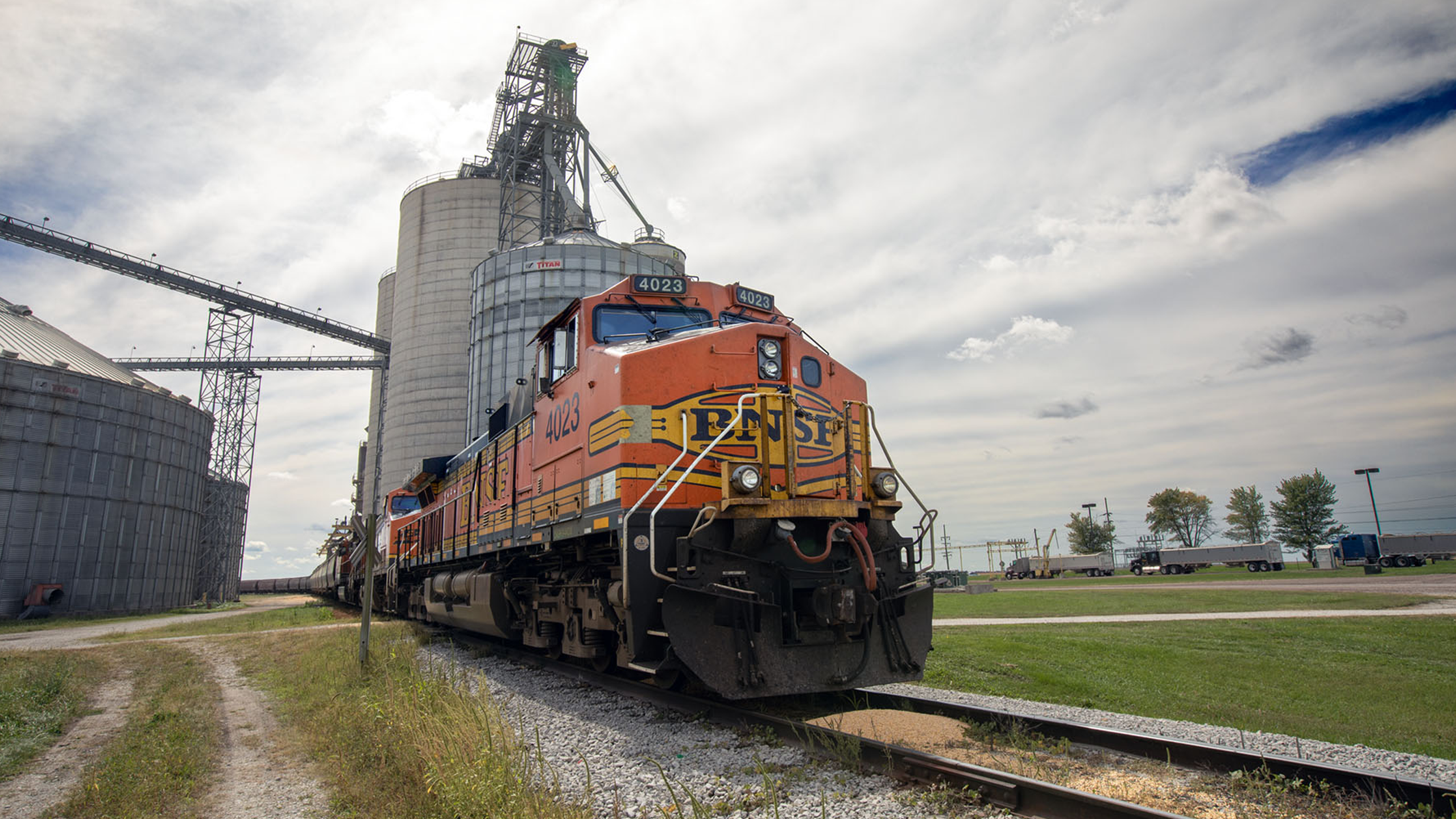 Image of a modern day train with a grain elevator in the background.