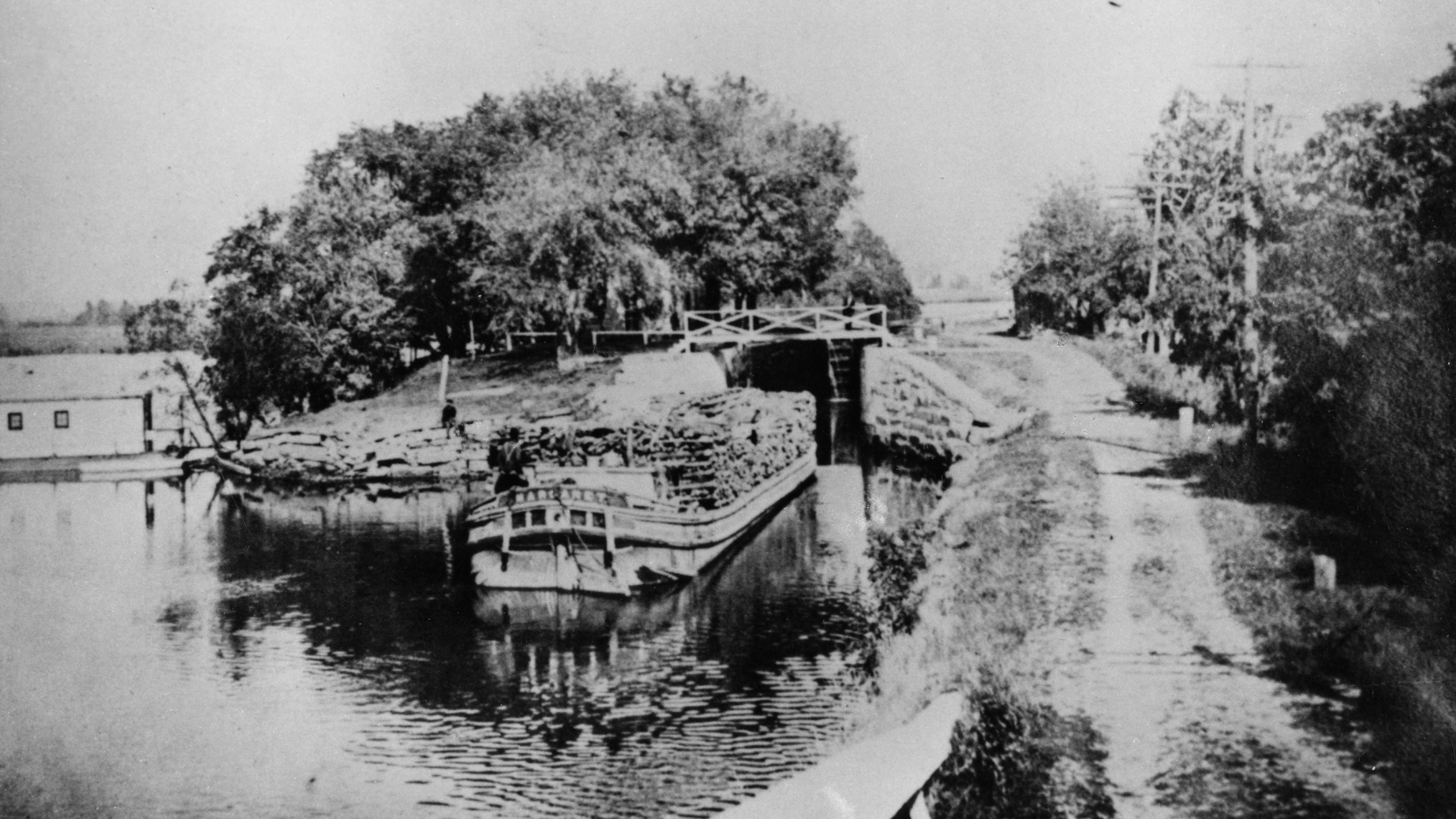 Old black and white photo of a canal boat entering Lock 6 at Channahon, Illinois.